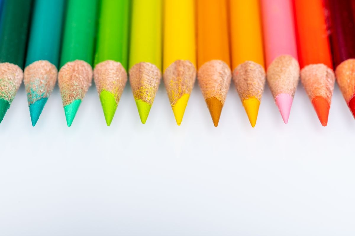 A neat row of sharpened colored pencils on a white surface.